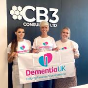 Jenny Ballantyne (centre) with her CB3 Consulting colleagues Summer Bennett (left) and Chelsea Allgood (right) holding a Dementia UK banner.