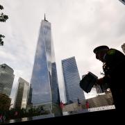 A New York Police Department officer holds US flags next to the reflecting pools at the memorial (Jeenah Moon, Pool/AP)